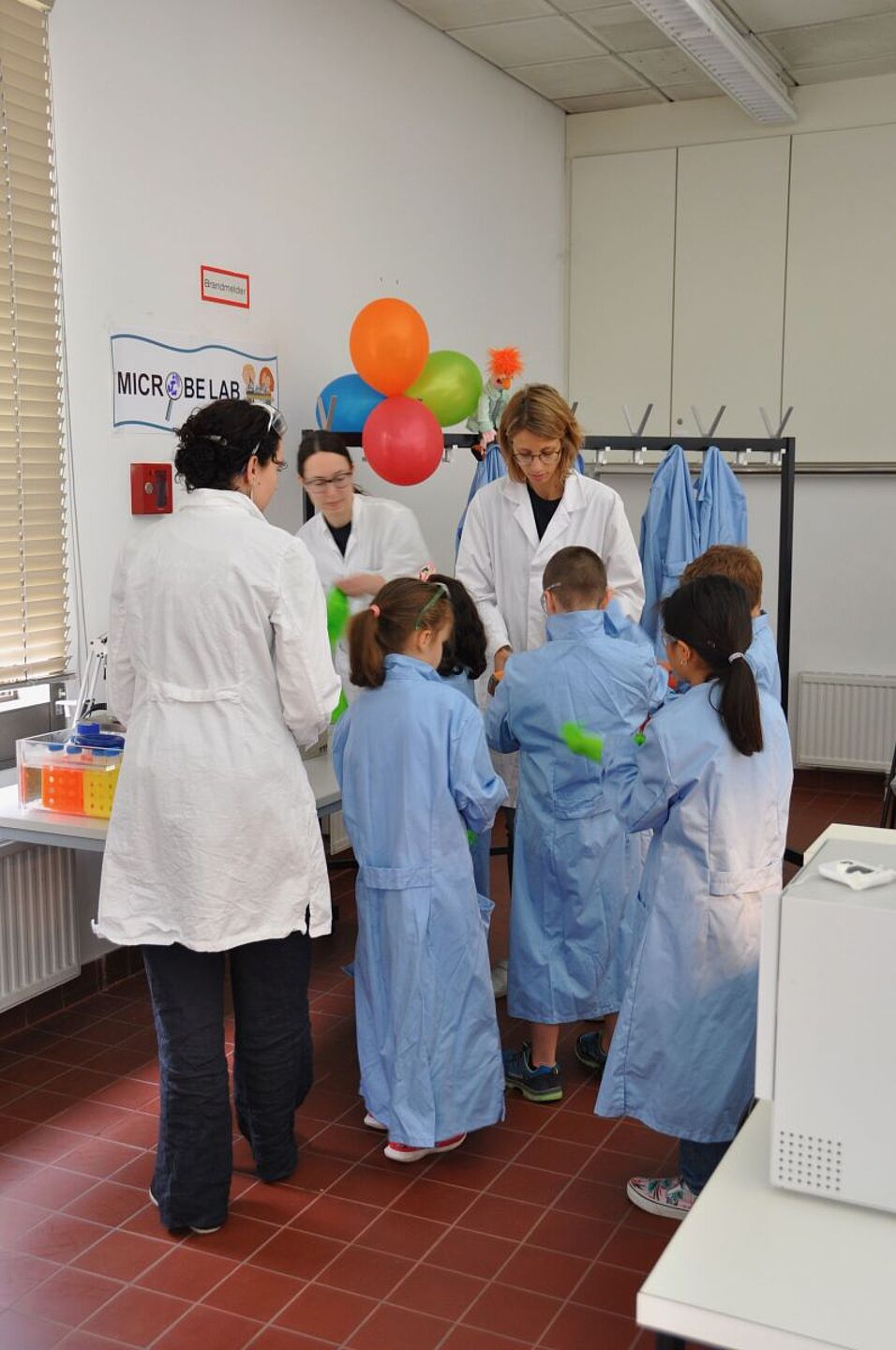 Children trying on big lab coates, safety goggles and gloves